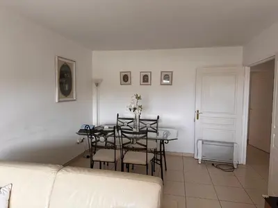 a living room with a table and chairs and a couch at 2 bedroom apartment with a pool in the heart of Cannes easy walk to the main beach on La Croisette - 2191 in Cannes