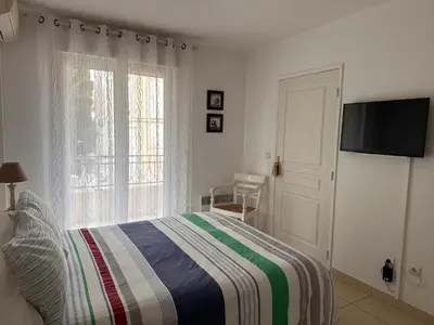 a bedroom with a bed with a striped blanket and a window at 2 bedroom apartment with a pool in the heart of Cannes easy walk to the main beach on La Croisette - 2191 in Cannes