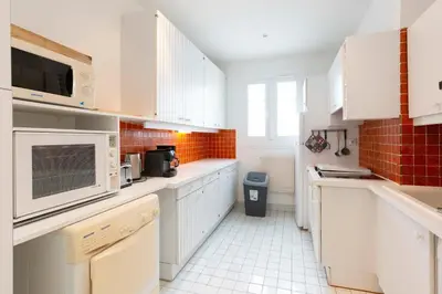 a kitchen with white cabinets and a white tiled floor at Selvosa 1-bedroom apartment heart of Cannes in Cannes