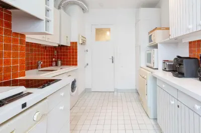 a kitchen with white cabinets and a white tiled floor at Selvosa 1-bedroom apartment heart of Cannes in Cannes