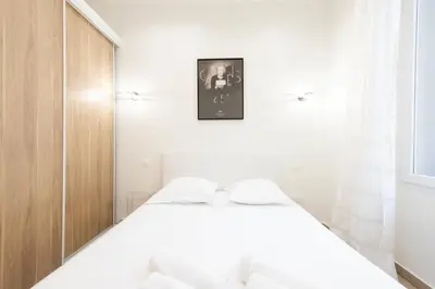 a bedroom with a white bed and a wooden cabinet at Renovated Apartment in the Heart of Cannes in Cannes