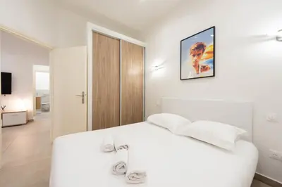 a white bedroom with a white bed and a picture on the wall at Renovated Apartment in the Heart of Cannes in Cannes