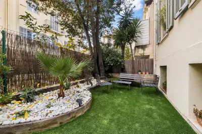 a small backyard with a bench and grass at L'Urban - 3 chambres - 9 min Palais - Climatisé in Cannes
