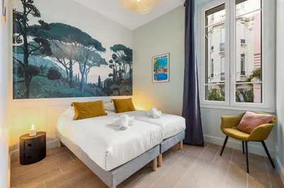 a bedroom with a bed and a painting on the wall at L'Urban - 3 chambres - 9 min Palais - Climatisé in Cannes