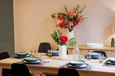 a table with plates and glasses and a vase with flowers at L'Urban - 3 chambres - 9 min Palais - Climatisé in Cannes