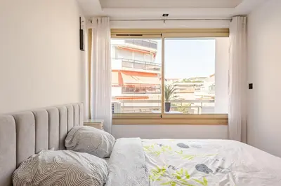 a bedroom with a bed and a window with a building at Plage luxe collé à l’hôtel Martinez in Cannes