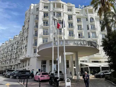 a large white building with cars parked in front of it at Plage luxe collé à l’hôtel Martinez in Cannes
