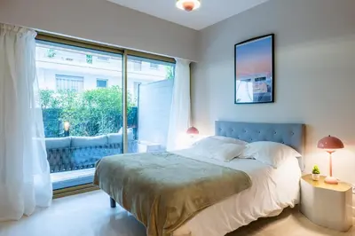 a bedroom with a bed and a large window at Downtown Cannes Apartment with Garden in Cannes