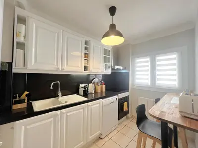 a kitchen with white cabinets and a sink and a table at Savannah appartement proche Carlton, by Welcome to Cannes in Cannes