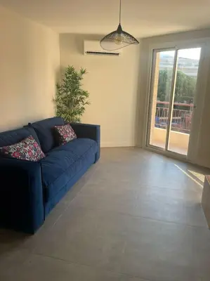 a living room with a blue couch and a window at Appartement MARTINEZ 5 couchages in Cannes