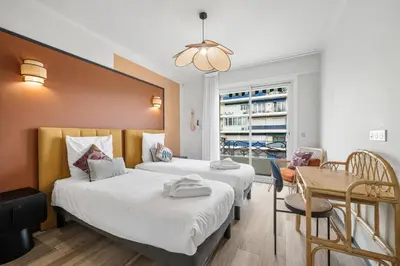 a hotel room with two beds and a table at Jessicannes - COOPER - 3 chambres - Central, spacieux, terrasse in Cannes