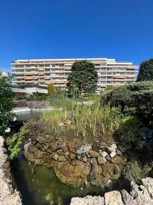 a building with a garden in front of a pond at Mimosas by Welcome to Cannes in Cannes
