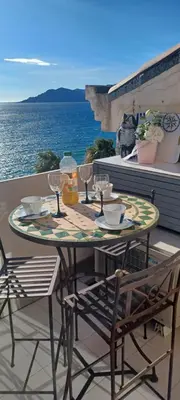 a table and chairs on a balcony with the ocean at Ciel Bleu de Cannes - Appartement Vue Azur avec Piscines et Jardin in Cannes