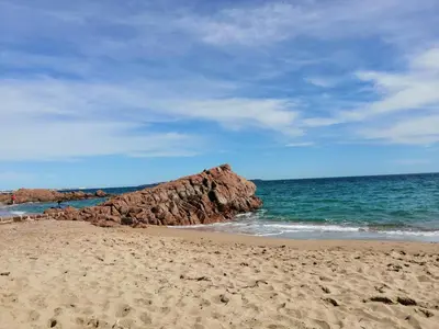 a sandy beach with a large rock in the ocean at Ciel Bleu de Cannes - Appartement Vue Azur avec Piscines et Jardin in Cannes