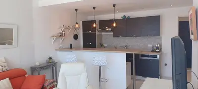 a kitchen with brown cabinets and a counter top at Ciel Bleu de Cannes - Appartement Vue Azur avec Piscines et Jardin in Cannes