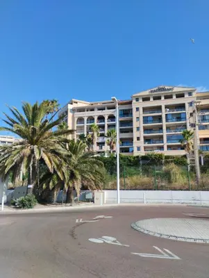 an empty parking lot with palm trees and a large building at Ciel Bleu de Cannes - Appartement Vue Azur avec Piscines et Jardin in Cannes