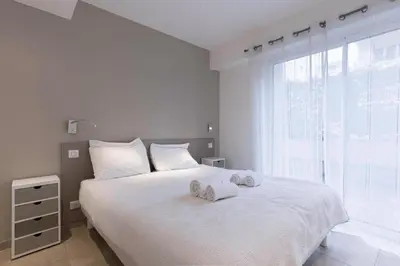 a white bedroom with a large bed with towels on it at Jardin d'Azur – Terrace, Calm & Croisette in Cannes