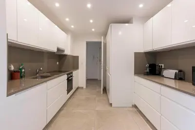 a white kitchen with white cabinets and appliances at Jardin d'Azur – Terrace, Calm & Croisette in Cannes