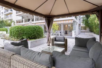 an outdoor patio with couches and an umbrella at Jardin d'Azur – Terrace, Calm & Croisette in Cannes