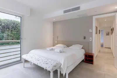 a bedroom with a white bed and a large window at Jardin d'Azur – Terrace, Calm & Croisette in Cannes