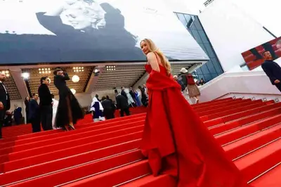 a woman in a red dress walking down the red carpet at Studio 6minutes Croisette cannes in Cannes