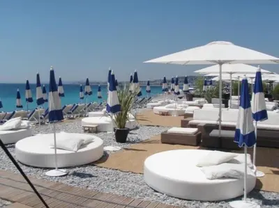 a group of lounge chairs and umbrellas on a beach at Cannes Palm Beach Parking, clim, wifi plage 2' à pieds in Cannes