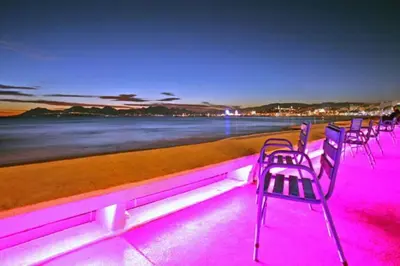 a row of chairs on a beach with pink lights at Cannes Palm Beach Parking, clim, wifi plage 2' à pieds in Cannes