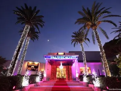 a pink building with palm trees in front of it at Cannes Palm Beach Parking, clim, wifi plage 2' à pieds in Cannes