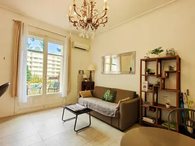 a living room with a couch and a chandelier at Mythique Miramar Cannes Croisette Terrasse Clim Parking Wifi in Cannes