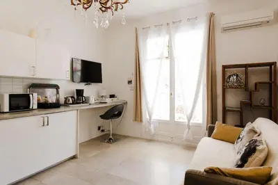 a white living room with a couch and a window at Mythique Miramar Cannes Croisette Terrasse Clim Parking Wifi in Cannes