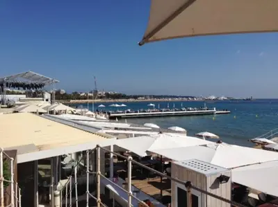 a marina with white umbrellas and a dock with boats at Mythique Miramar Cannes Croisette Terrasse Clim Parking Wifi in Cannes