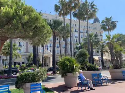 a man sitting on a chair in front of a building at Mythique Miramar Cannes Croisette Terrasse Clim Parking Wifi in Cannes