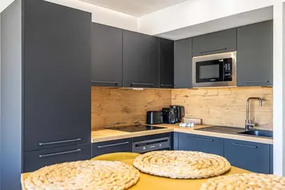 a kitchen with blue cabinets and a table with two stools at 8 MERLE - Beau studio au centre de Cannes avec balcon ! in Cannes