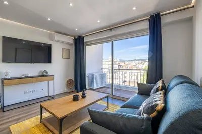 a living room with a blue couch and a large window at 8 MERLE - Beau studio au centre de Cannes avec balcon ! in Cannes