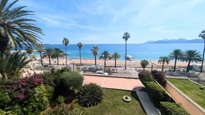 a view of a beach with palm trees and the ocean at Ref BELLAMARE in Cannes
