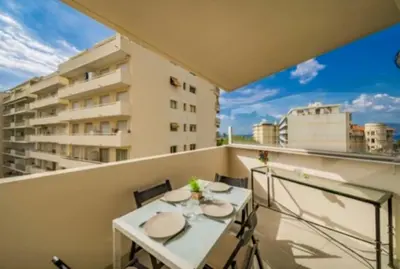 a balcony with a white table and chairs and a building at Magnifique studio au pied des plages in Cannes