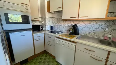 a small kitchen with white cabinets and a sink at Comfortable studio near the beaches in Cannes
