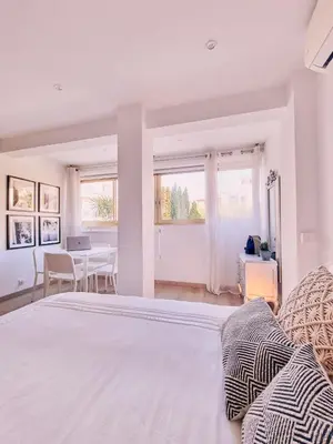 a white bedroom with a large bed and a table at Studio Latour Maubourg in Cannes