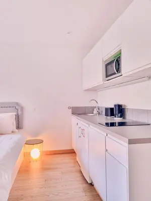 a white kitchen with a bed and a light on the floor at Studio Latour Maubourg in Cannes