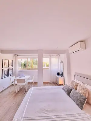 a white bedroom with a bed and a table at Studio Latour Maubourg in Cannes