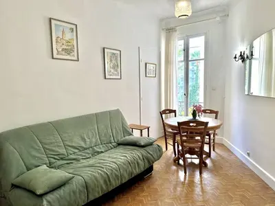 a living room with a green couch and a table at Cannes La Croisette - PALAIS MIRAMAR - Studio au calme coté jardin in Cannes