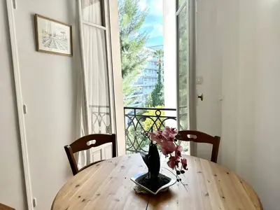 a wooden table with a vase with flowers on it at Cannes La Croisette - PALAIS MIRAMAR - Studio au calme coté jardin in Cannes