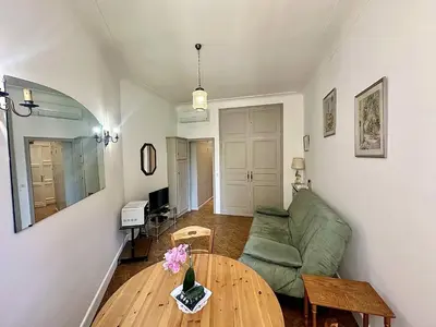 a living room with a green couch and a table at Cannes La Croisette - PALAIS MIRAMAR - Studio au calme coté jardin in Cannes