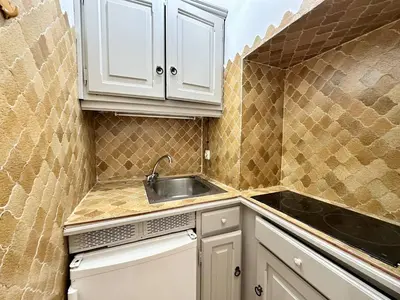 a small kitchen with white cabinets and a sink at Cannes La Croisette - PALAIS MIRAMAR - Studio au calme coté jardin in Cannes
