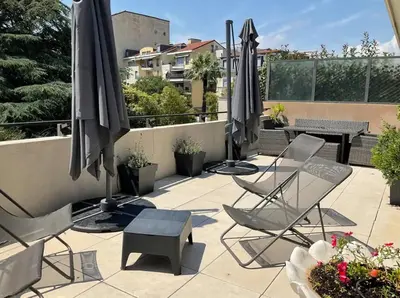 a patio with chairs and umbrellas and a table at Toit terrasse dans résidence avec piscine in Cannes