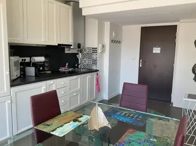 a kitchen with a glass table and two purple chairs at Toit terrasse dans résidence avec piscine in Cannes