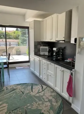 a kitchen with white cabinets and a view of a patio at Toit terrasse dans résidence avec piscine in Cannes