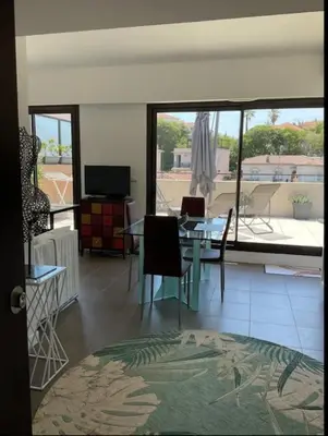 a dining room with a table and chairs and a large window at Toit terrasse dans résidence avec piscine in Cannes
