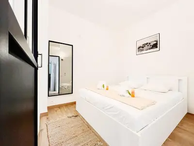 a white bedroom with two beds and a mirror at L’Iris - Suquet Cannes Centre in Cannes