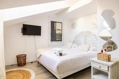 a white bedroom with two beds and a flat screen tv at WELCOME - Stunning 2-bedroom at 5 minutes from Palais des Festivals in Cannes